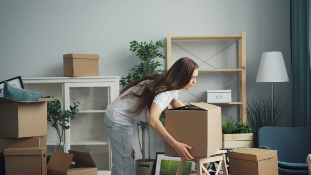 A woman packing moving boxes in a living room