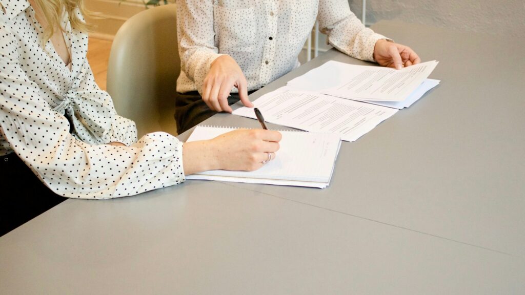 A person signing a document at a desk