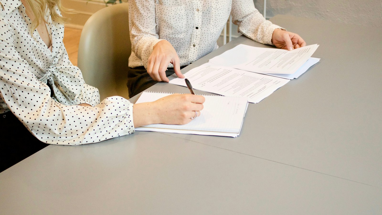 A person signing a document at a desk