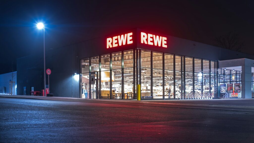 A REWE supermarket lit up at night in Germany
