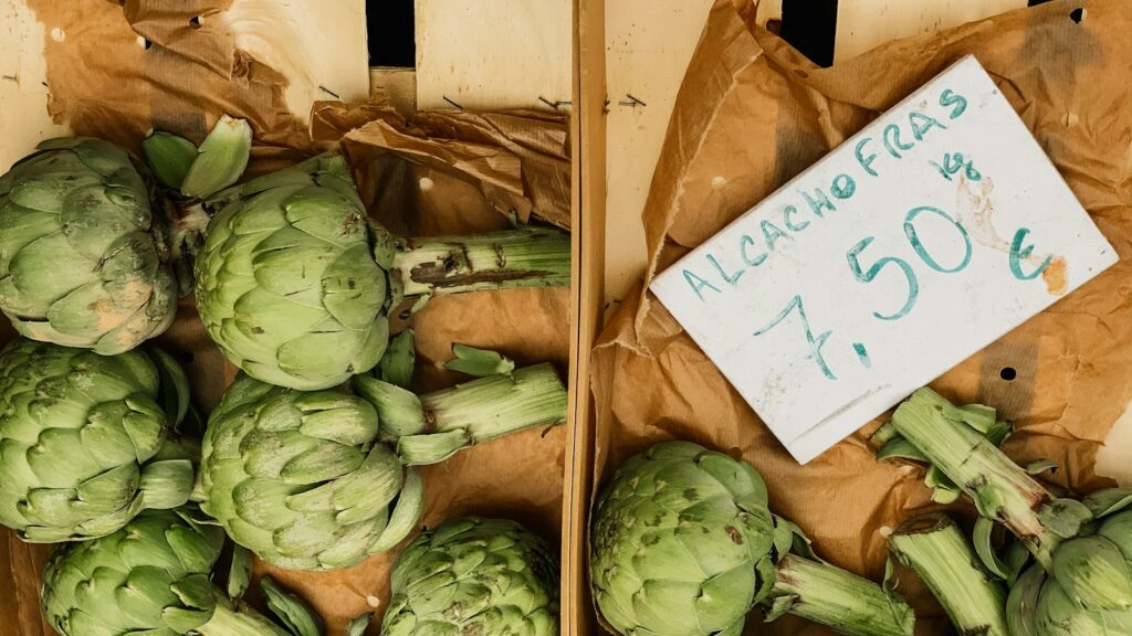 Artichokes at a Portuguese market with a handwritten price sign reading alcachofras 7,50 euros