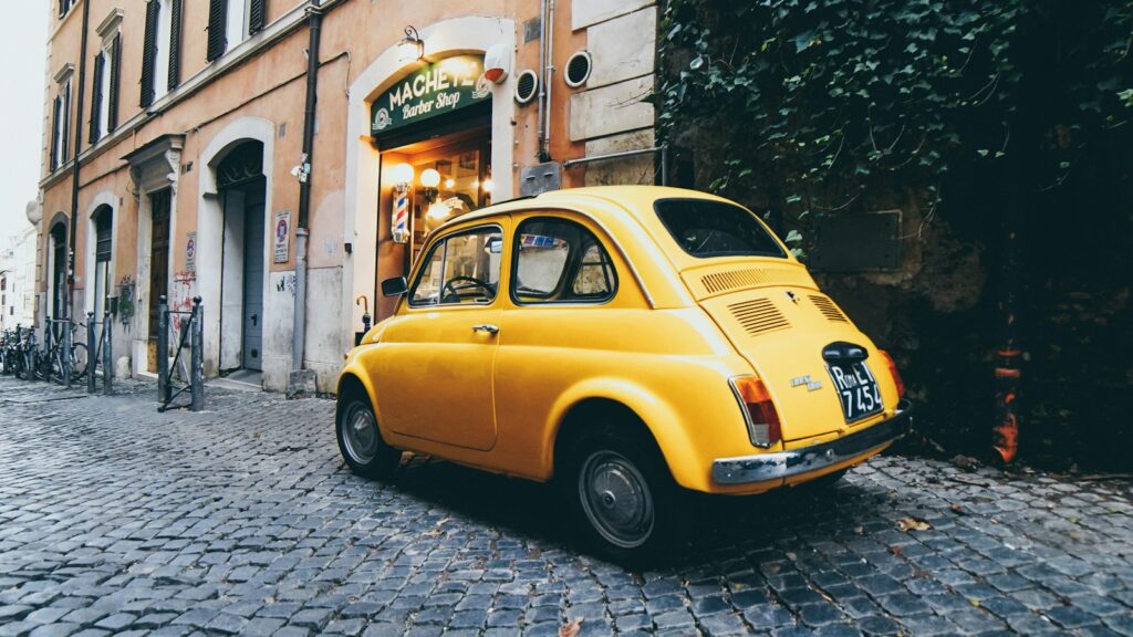 A yellow Fiat 500 parked on a street in Rome, Italy