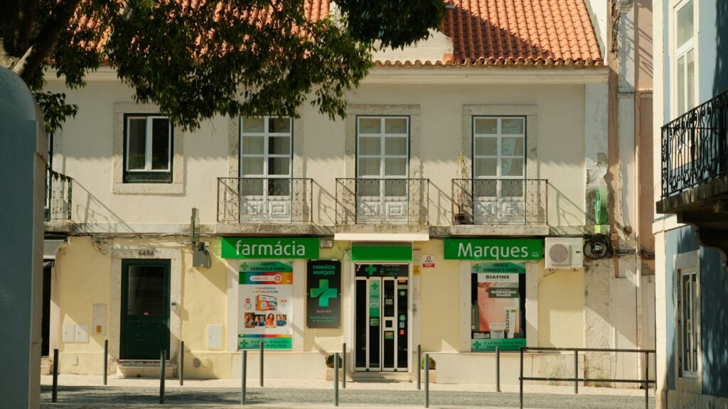 A pharmacy with a green sign on a sunny street in Portugal