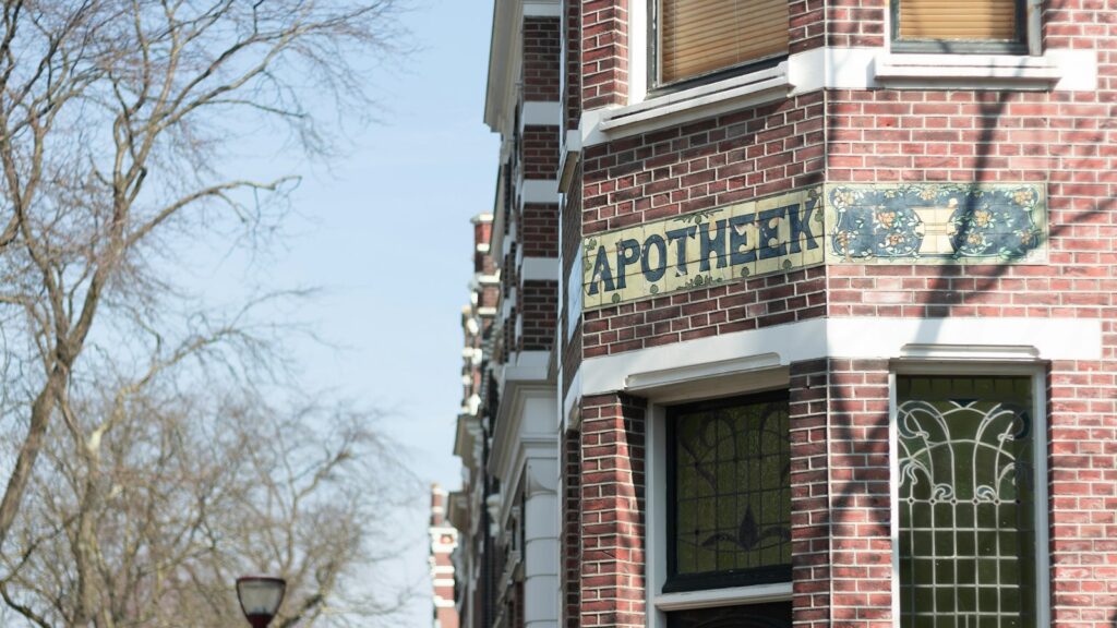 A traditional tiled Apotheek pharmacy sign on a Dutch brick building