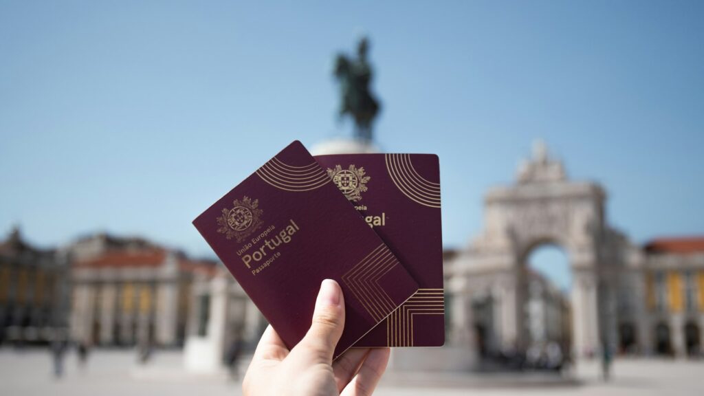 Portuguese passports held up in front of the arch at Praça do Comércio, Lisbon