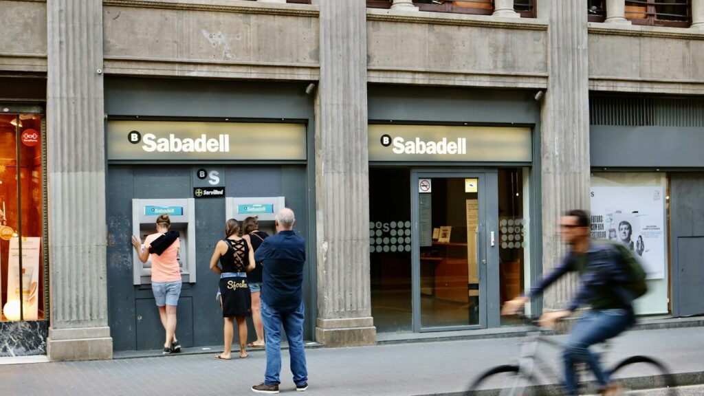People using the cash machines outside a Banco Sabadell branch in Spain