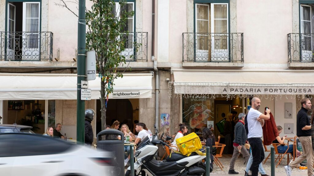 People walking past cafés and shops on a street in Lisbon