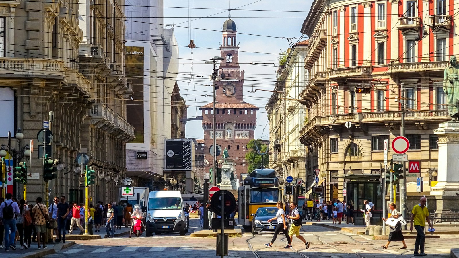 A busy city street leading towards the Castello Sforzesco in Milan, Italy